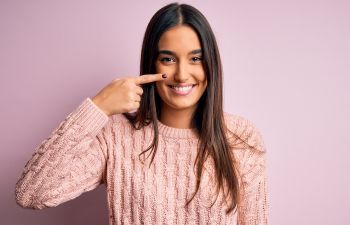 Young smiling woman pointing at her nose.